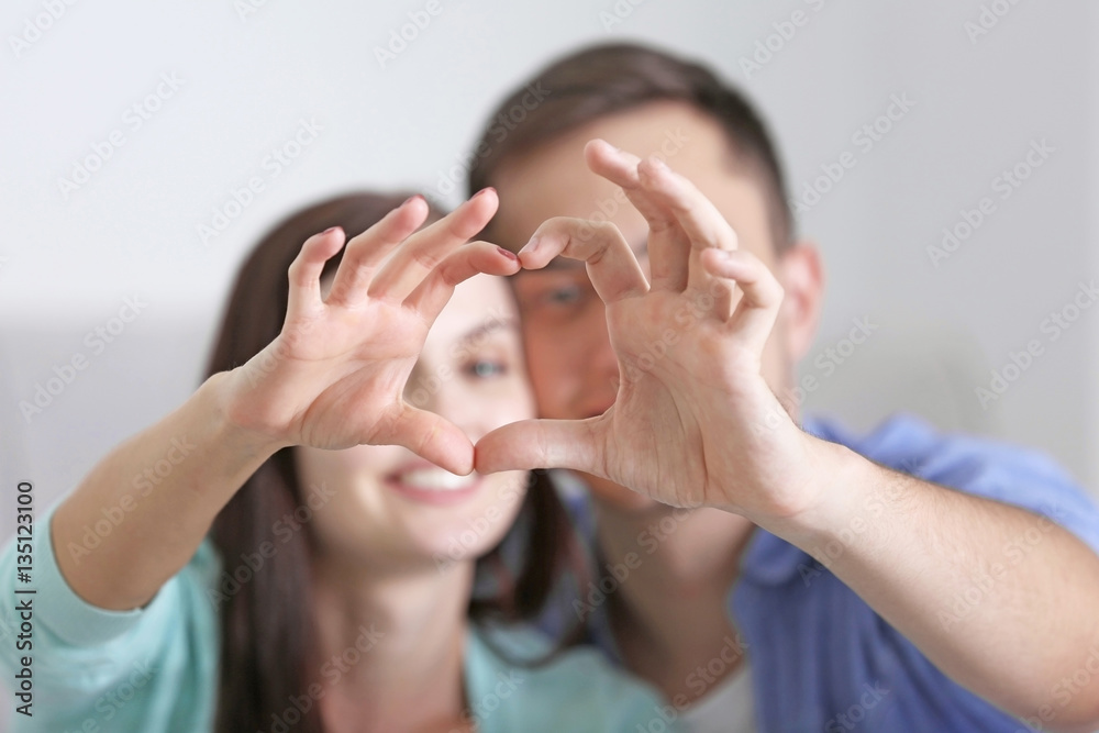 Wall mural Happy couple making heart by hands