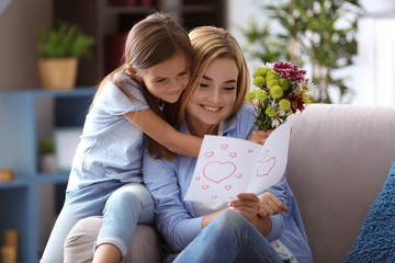 Cute little girl greeting her mother at home. Mother's day concept