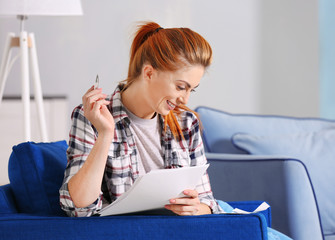 Beautiful young woman calculating taxes at home