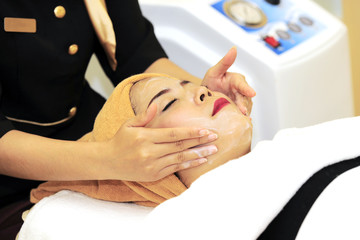 Asian woman do spa beauty salon acne treatment using mechanical instrument. Concept of medical treatment of rejuvenation and skincare. Woman receiving facial mask. Woman face beauty Treatment