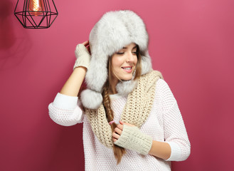 Beautiful young woman with warm hat on color background