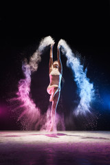 Young girl streching in jump in color dust cloud