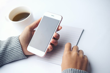 Female hand writing down on letter paper with cup of tea on the wood desk, top view