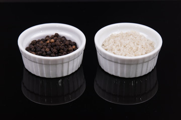 Course gray salt and peppercorns in smal ramekins on reflective