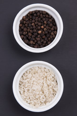 Course gray salt and peppercorns in smal ramekins on matte blac