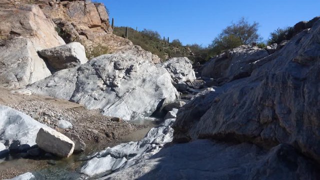 A daytime low angle establishing shot of a small stream in the rocky Arizona desert.	 	