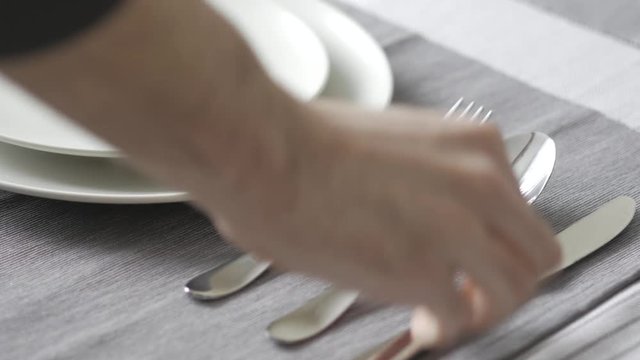 Placing the utensils on the dining table. Modern kitchen table with cutlery and plates.