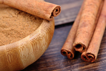 Cinnamon powder in a bamboo bowl with cinnamon sticks