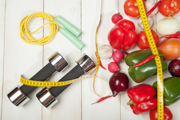 Fototapeta na wymiar Sport and diet. Healthy lifestyle. Vegetables, dumbbells. Peppers, tomatoes, garlic, onions radishes on a white background