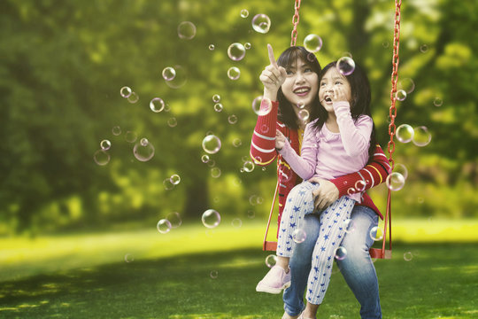 Young Mother And Child Sitting On Swing