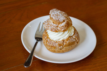 Cream puffs filled vanilla custard and dusted with icing on a rack