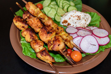 Chicken kebab with vegetables on a clay plate