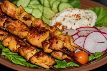 Chicken kebab with vegetables on a clay plate