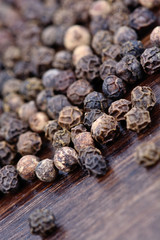 Black peppercorns on wooden background