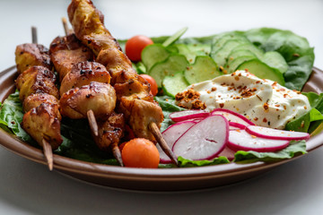 Chicken kebab with vegetables on a clay plate