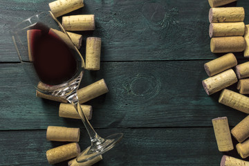 Glass of red wine and corks on dark background © laplateresca