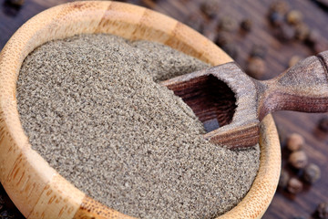 Peppercorns powder in a bamboo bowl with wooden scoop