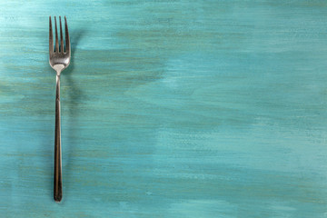 Vintage fork on vibrant turquoise with copyspace