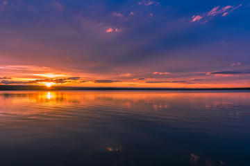 Summer landscape with river, forest, clouds on the blue sky and sunset. 