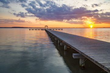 Fototapeta premium wooden pier overlooking the lake, the beautiful evening sky, colored by the setting sun 