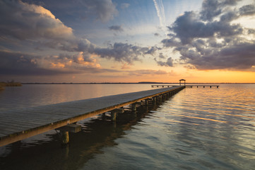 Fototapeta premium drewniane molo z widokiem na jezioro, piękne wieczorne niebo, zabarwione przez zachodzące słońce