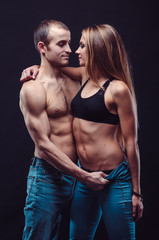 Sexy couple in jeans. Boyfriend and girlfriend embracing in the dark.
