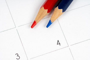 red and blue pencils on empty calendar grid