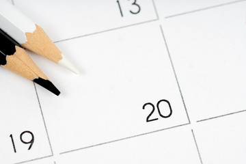 black and white pencils on empty calendar grid