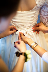 Obraz na płótnie Canvas Bride fees. bridesmaid helps to fasten a corset