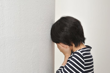壁の前で泣く女性