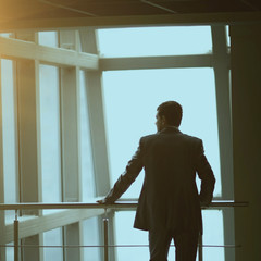 Portrait of pensive businessman standing with his back to the camera in front  a window