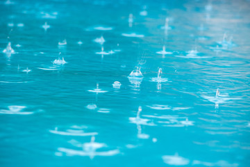 Close up of rain drops falling in the swimming pool. 
