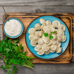 Ravioli on the wooden board with sauce and parsley