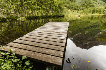 Old wooden pier on lake pond in summer