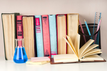 Open book, stack of colorful hardback books on light table. Back to school. Copy space for text