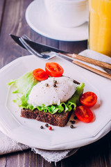 Rye Bread Toast and Poached Egg with Green Salad, Cherry tomato, cup of coffee and Orange Juice on the Wooden Table Background. Healthy Breakfast content