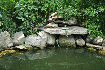 Artificial garden pool with natural stones and green plants. Detail of beautification.