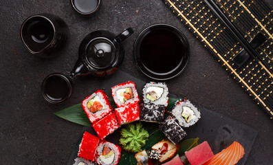 Japanese cuisine. Sushi set on a stone plate and black concrete background.