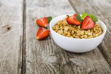 Granola with strawberry on a wooden table.