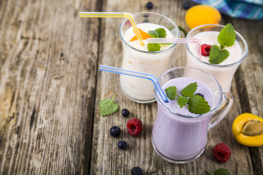 Smoothies or yogurt with fresh berries on a wooden table.