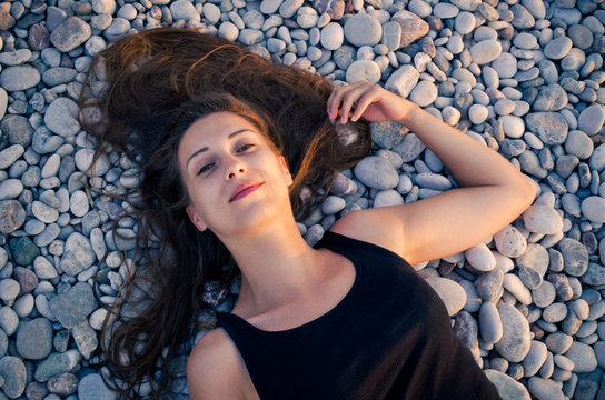 Woman lying on the beach covered by pebbles
