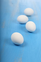 White eggs on a blue wooden background.