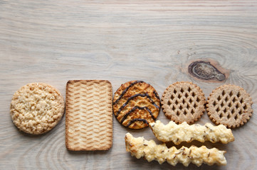 Several kinds of cookies with cheese, chocolate, peanuts on light wooden surface. Empty place.
