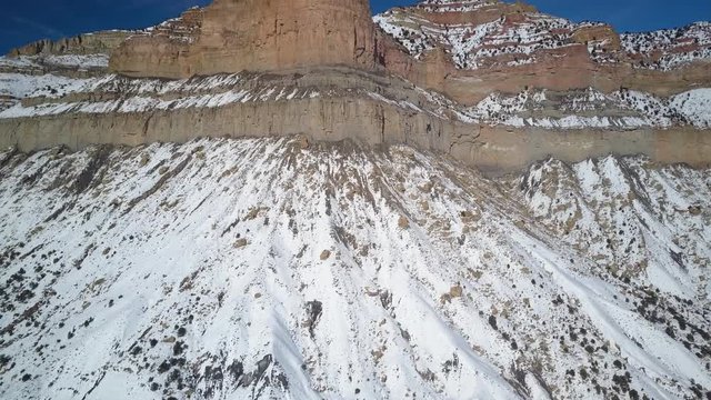 Aerial drone flight towards mountain cliff winter snow. Cold season weather. Nature environment. Beautiful natural environment. Rugged steep high desert. Drone flight.