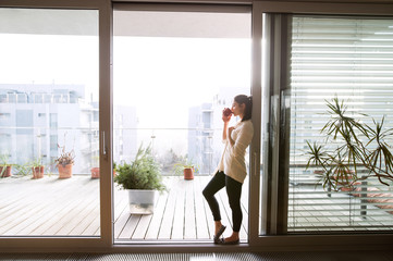 Fototapeta premium Kobieta relaksuje na balkonowej trzyma filiżance kawy lub herbacie