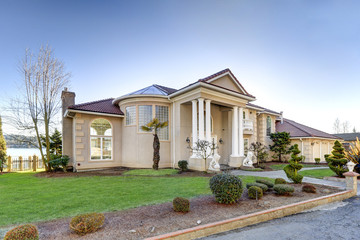 Mediterranean style waterfront home with stucco walls and columned porch