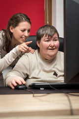 Pflegerin und geistig behinderte Frau am Computer, Bildung und T