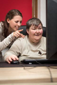 Pflegerin und geistig behinderte Frau am Computer, Bildung und T