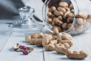 Peanuts in a jar on a white wooden background