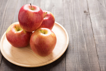 Fresh ripe red apples on dish wooden background.